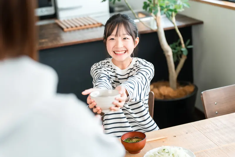 食卓で茶碗を渡す子ども