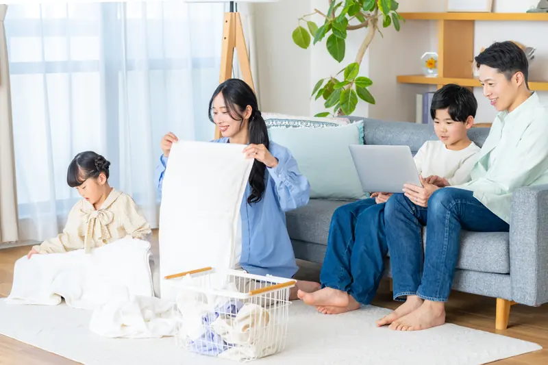 洗濯物を畳む親子とパソコンを使う親子