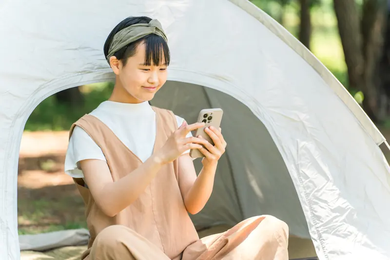 テントでスマートフォンを使う子ども