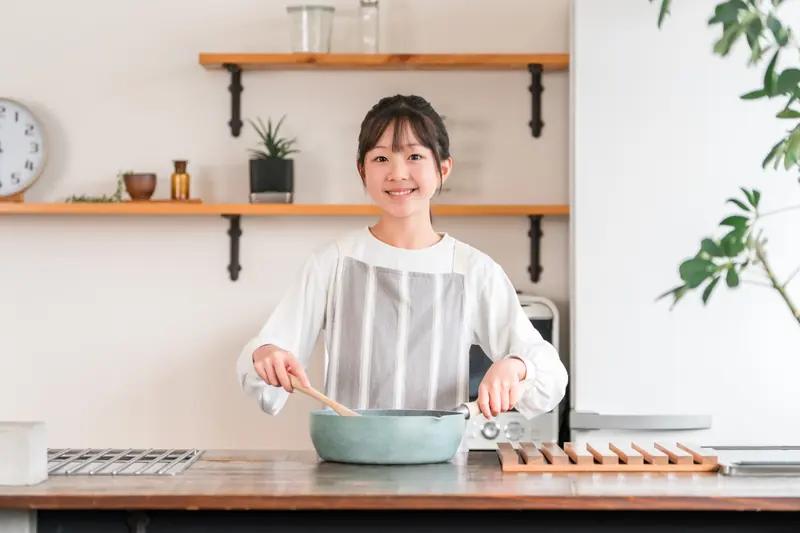 鍋を混ぜながら料理をする子ども