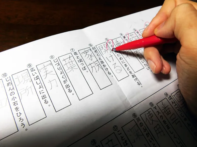 漢字のプリントを赤ペンで確認する手元